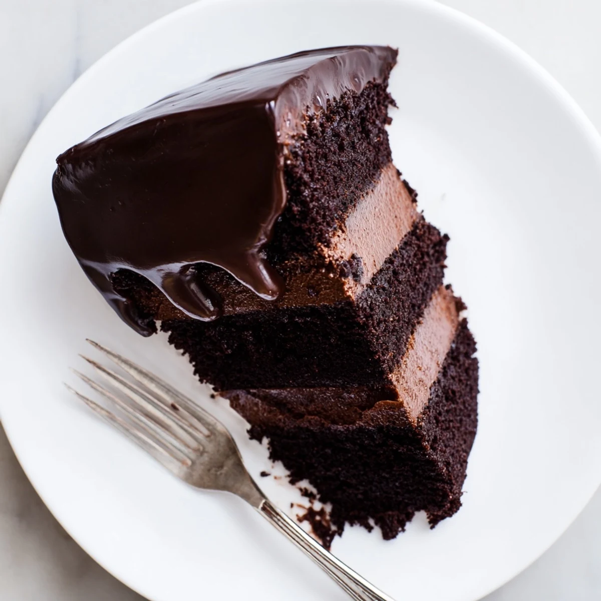 Slice of dark chocolate mousse cake revealing airy mousse between moist chocolate sponge layers