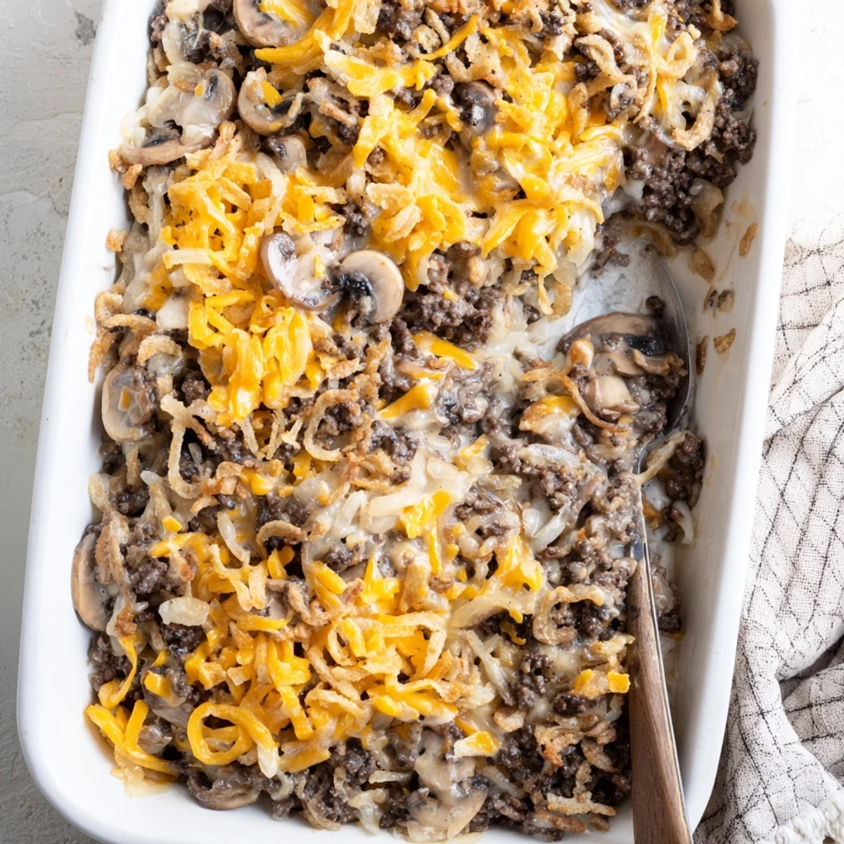 Hearty hamburger mushroom bake in a white baking dish with golden brown crust