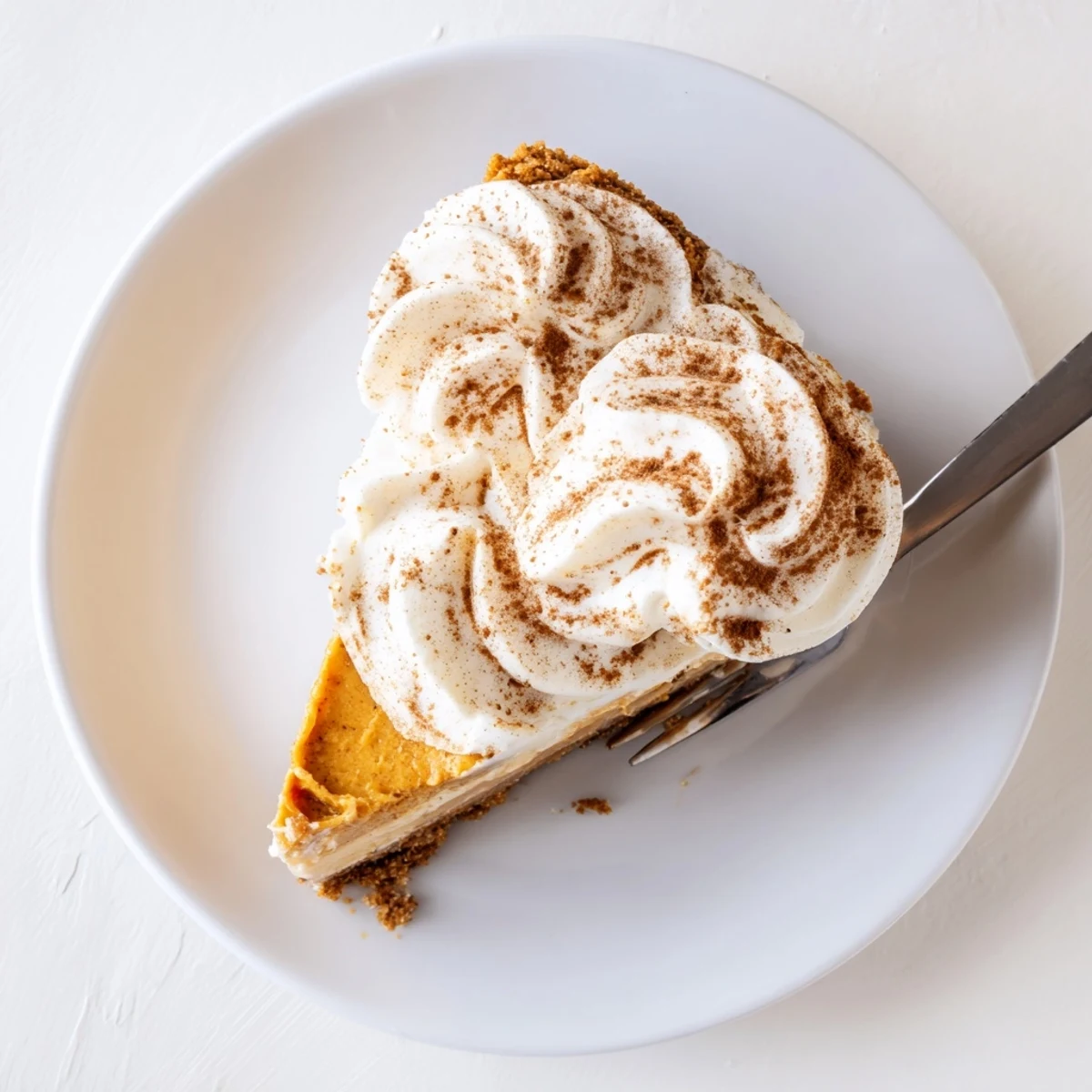 Rich pumpkin Christmas cheesecake with smooth spiced filling and billows of whipped cream on crunchy cinnamon crust
