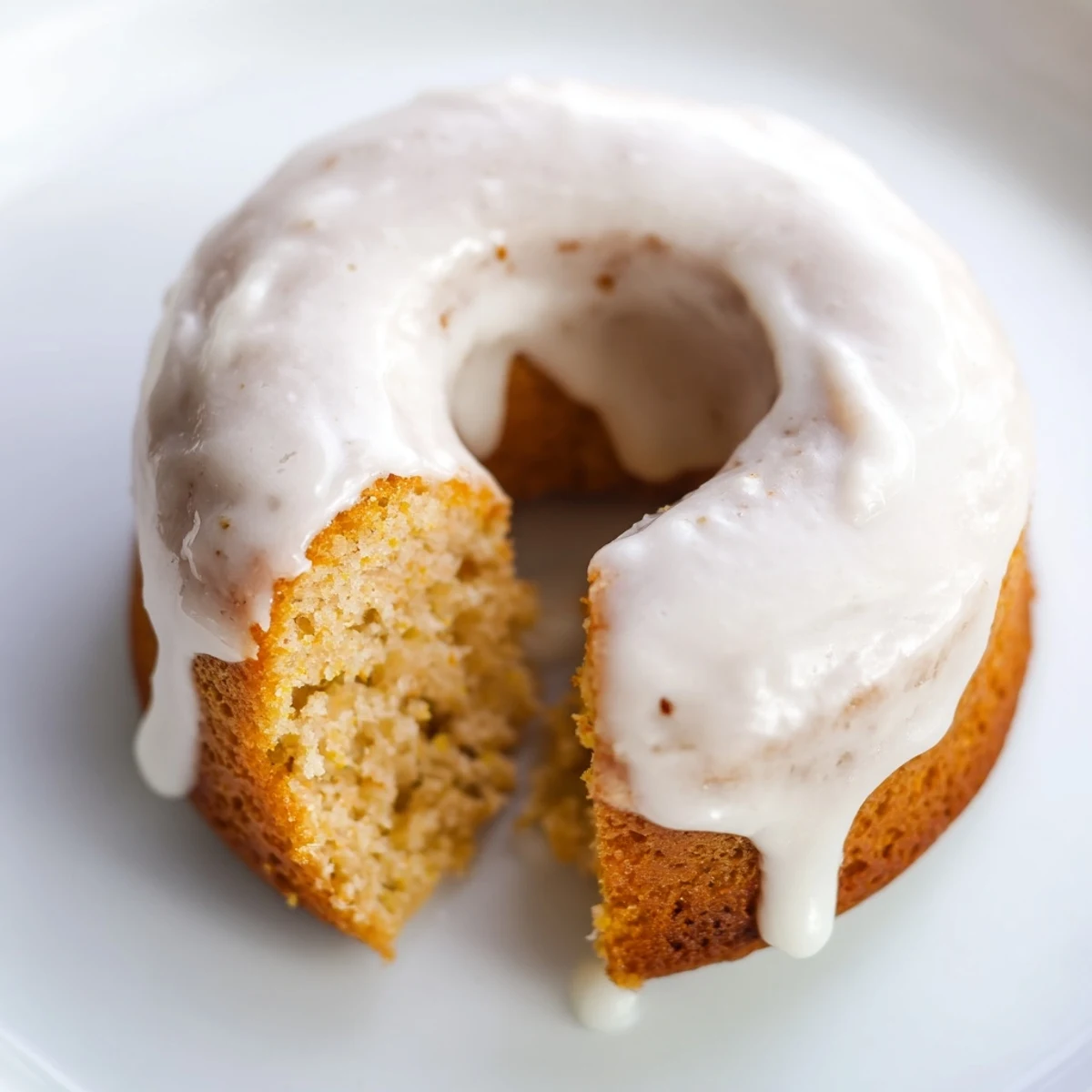Golden glazed Greek yogurt cake donuts cooling on a wire rack with sweet white icing dripping down the sides