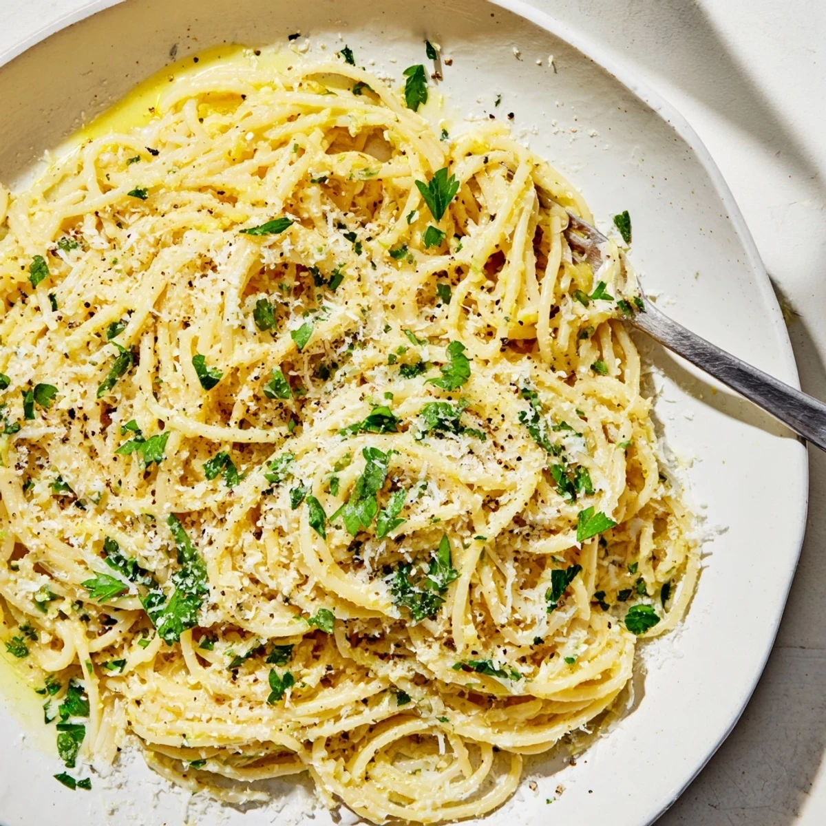 Creamy Parmesan lemon pasta twirled on a fork with fresh herb garnish and cracked black pepper