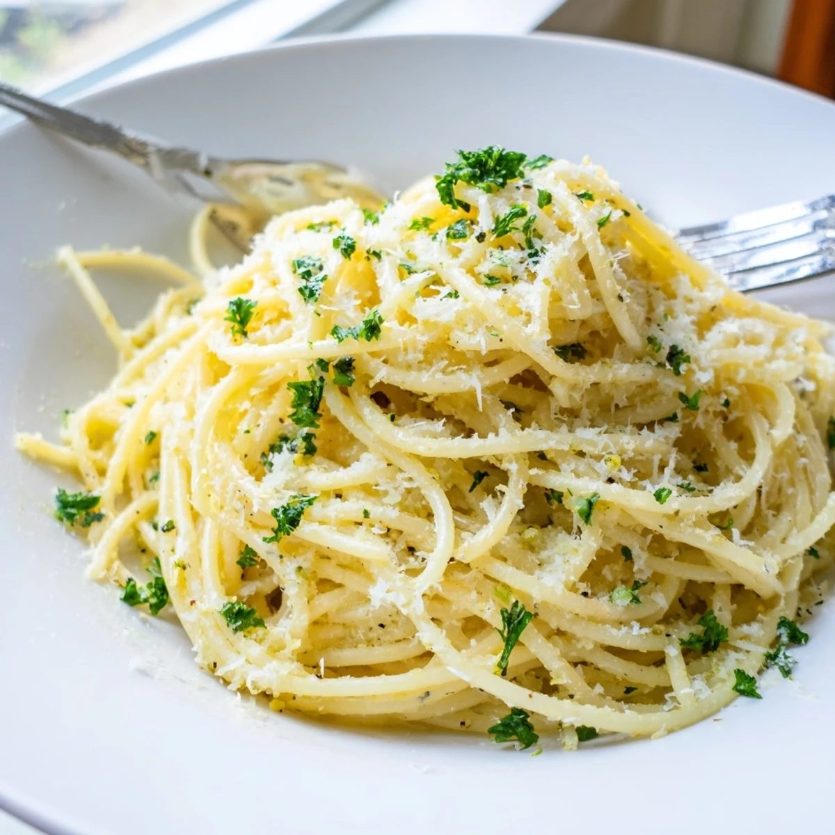 Golden buttery Parmesan lemon pasta in a white bowl topped with bright lemon zest