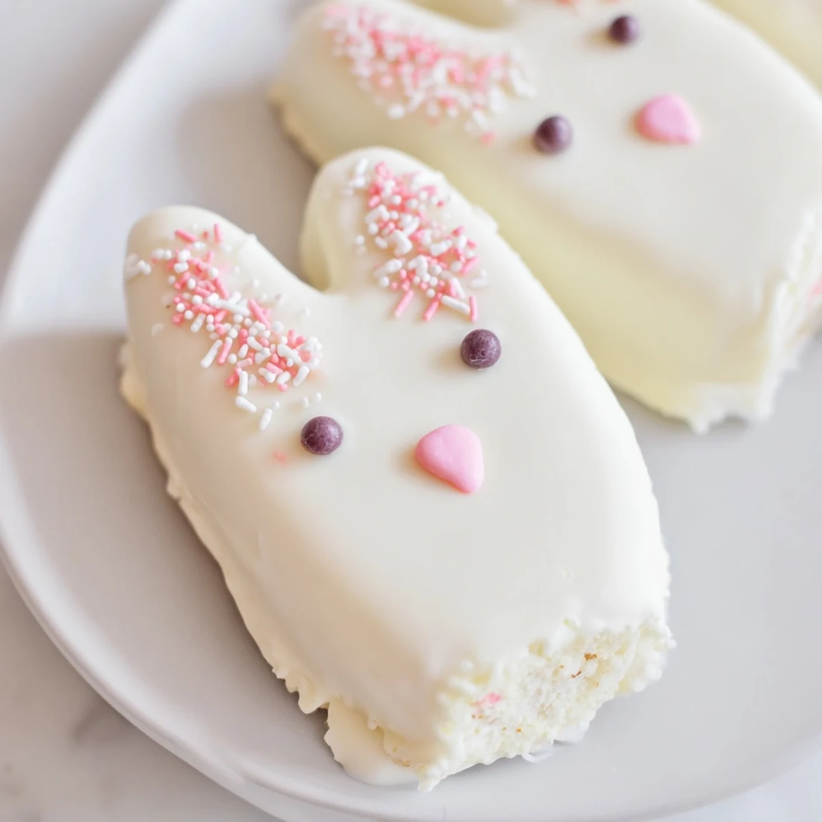 Adorable white chocolate bunny cakesicles with candy eyes and pink ears on sticks