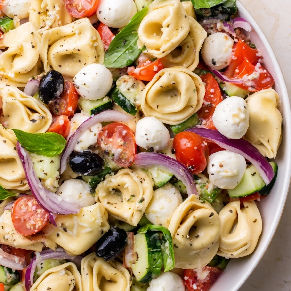 Colorful Tortellini Salad with cherry tomatoes, cucumber, and mozzarella in a zesty Italian dressing