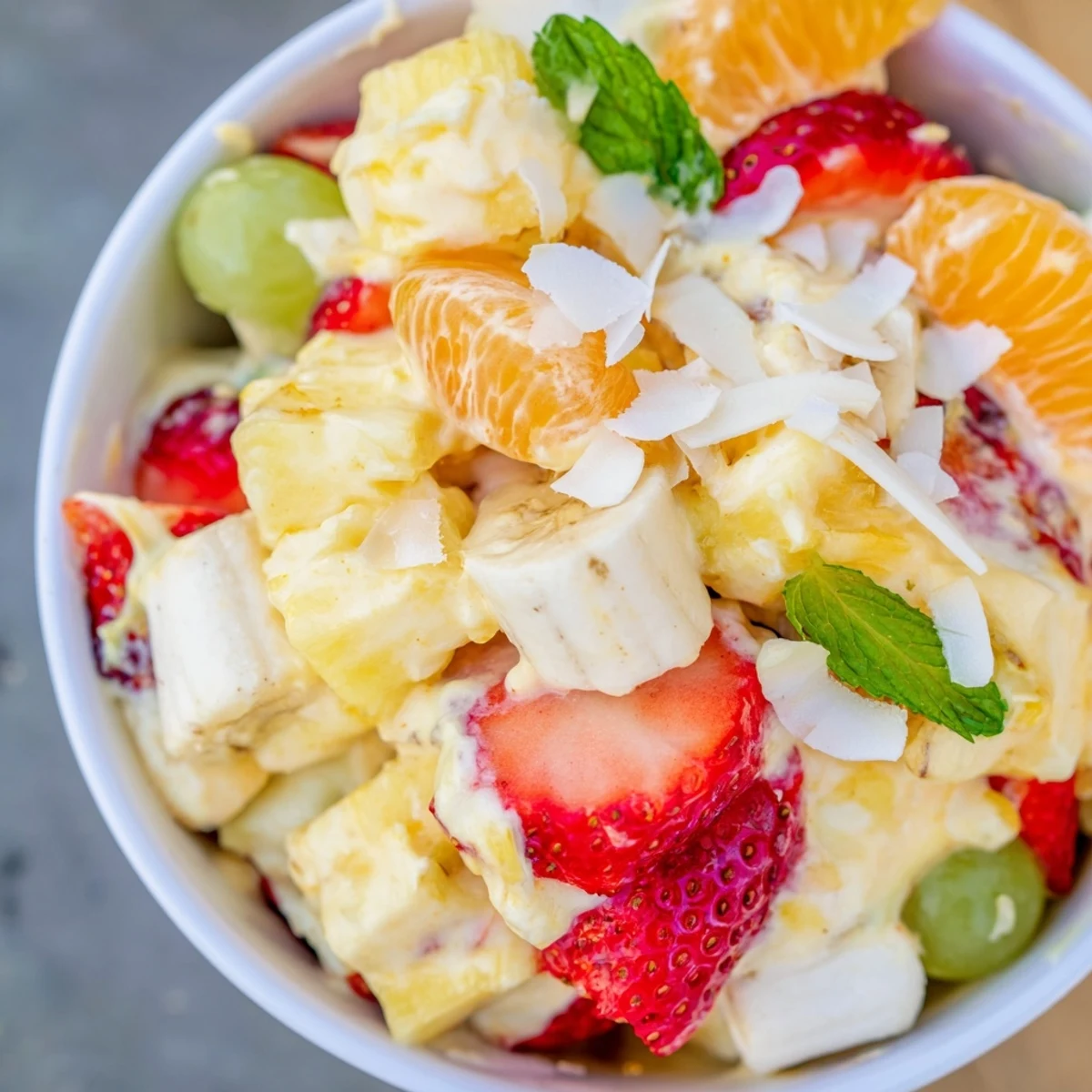 Creamy Hawaiian Cheesecake Salad topped with toasted coconut and fresh mint garnish