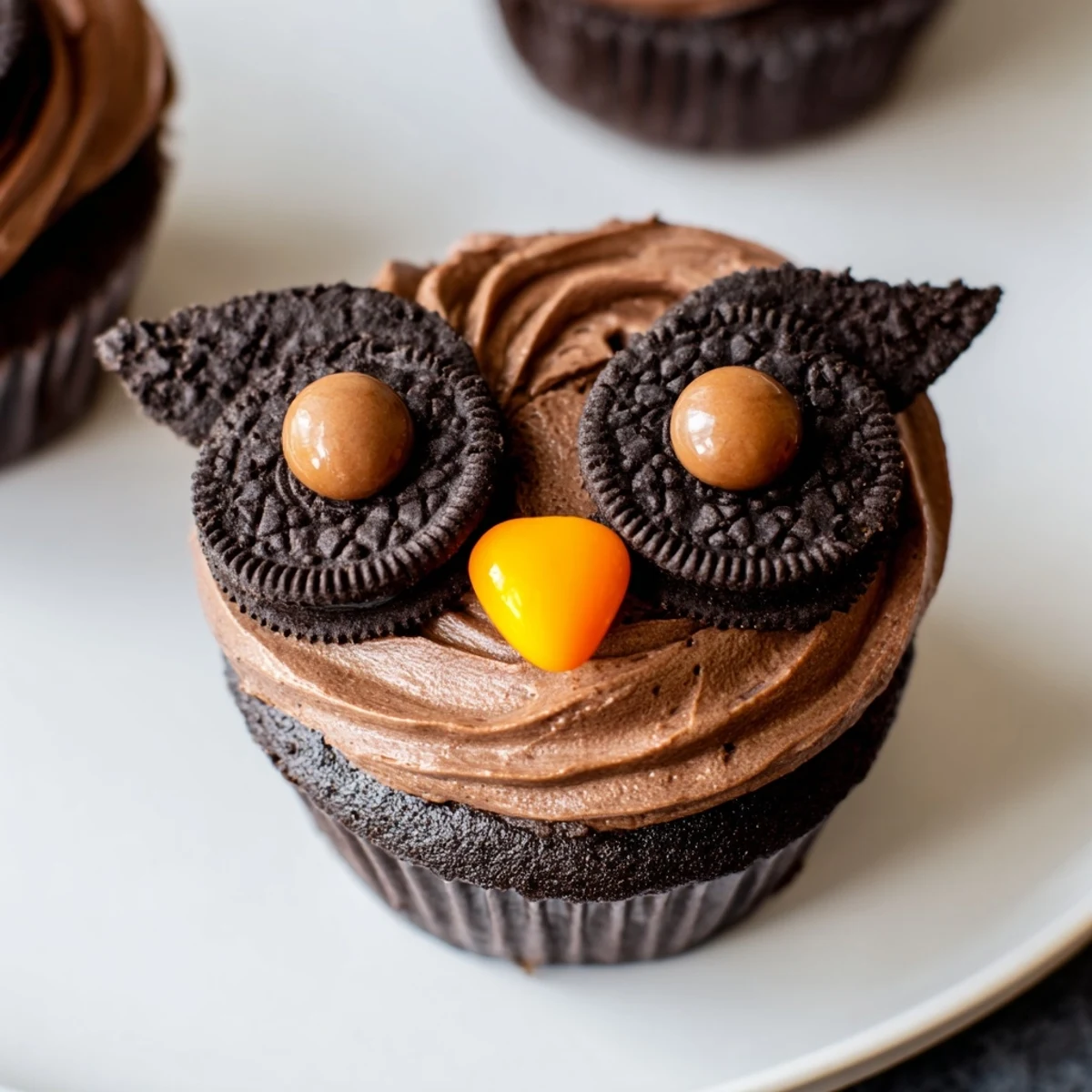 Chocolaty Oreo Owl Cupcakes topped with creamy frosting and adorable candy beak faces up close