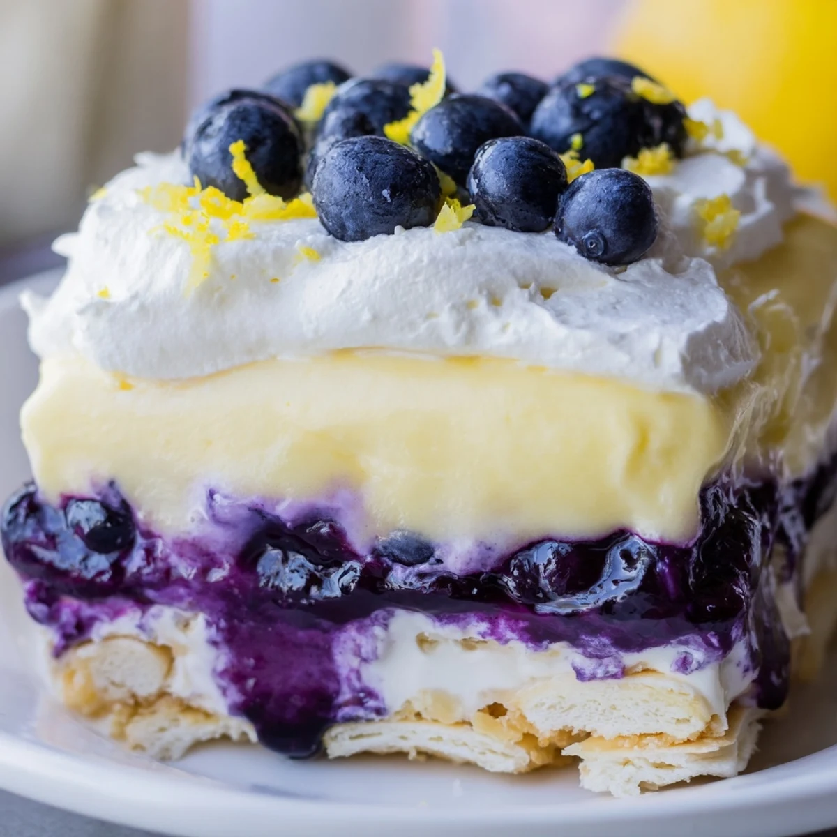 Creamy lemon blueberry lasagna dessert served on a white plate with zest sprinkle