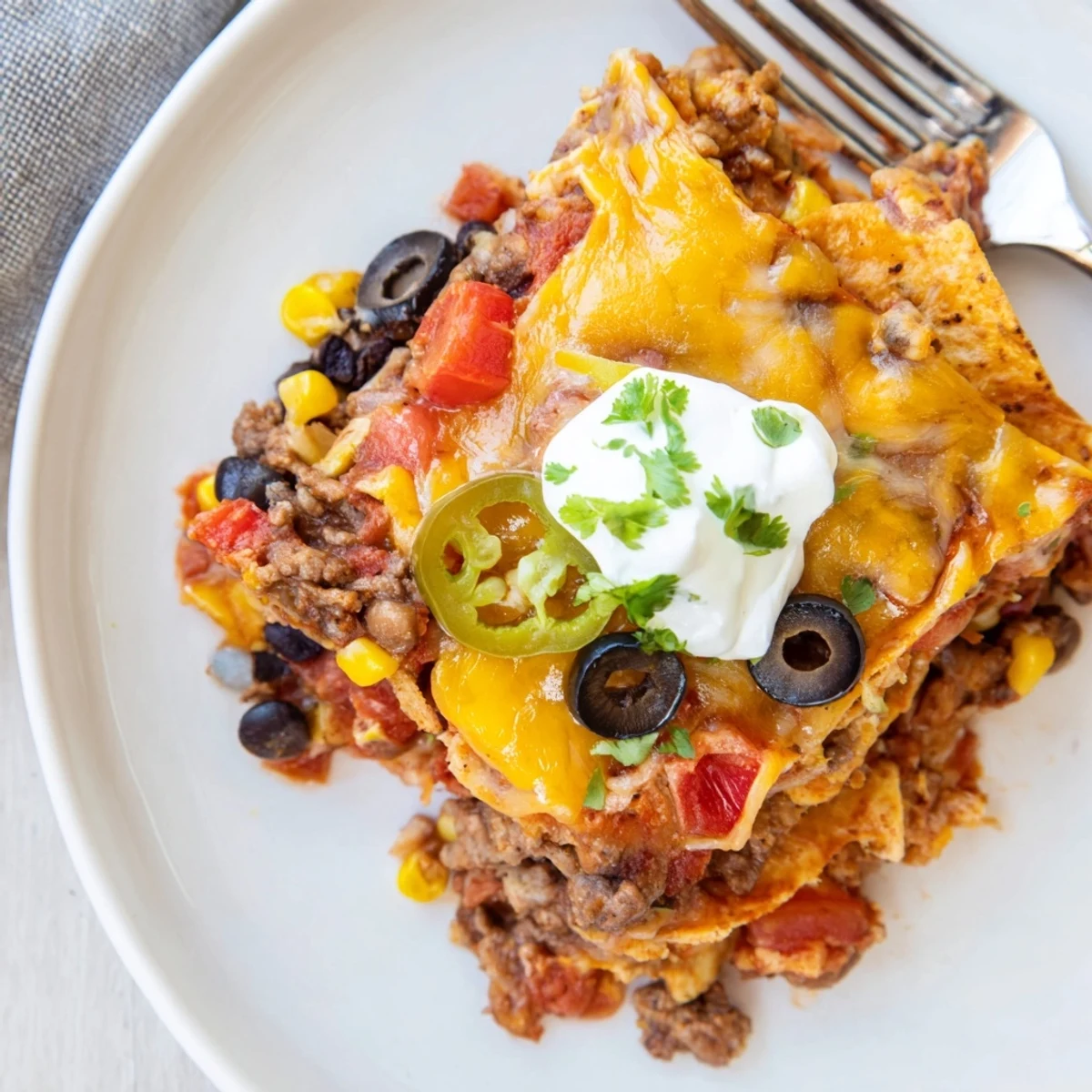 Warm Cheesy Nacho Casserole served with sour cream, cilantro, sliced jalapeños