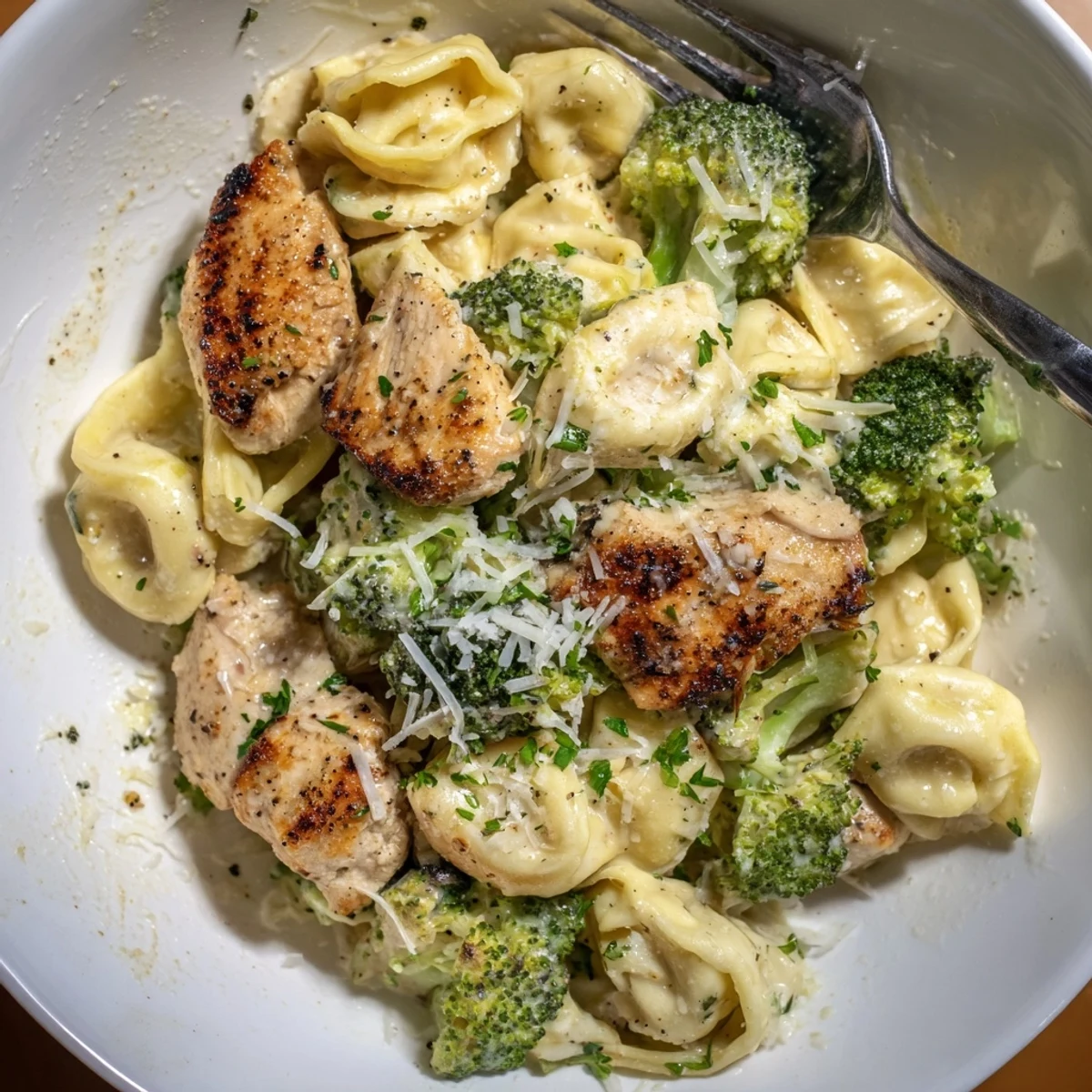 Spoon-ready bowl of Creamy Garlic Parmesan Tortellini Chicken Broccoli Recipe, fragrant garlic aroma.