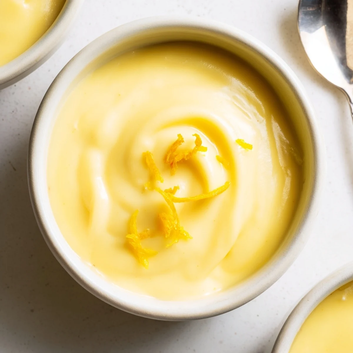 Silky, bright Lemon Curd Recipe cooling in sterilized jar beside whisk