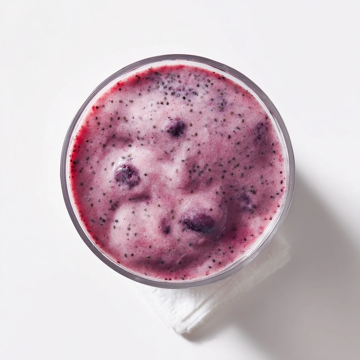 Thick purple chia seed smoothie topped with fresh berries in a clear glass
