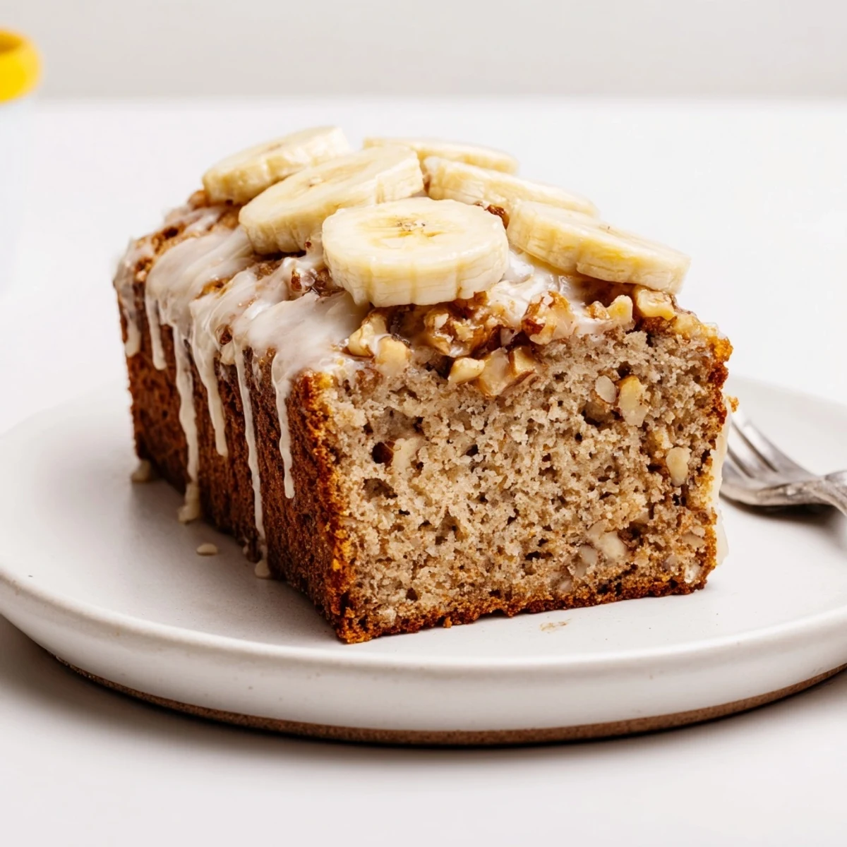 Slice of Moist Banana Cake on plate, tender crumb with toasted walnuts