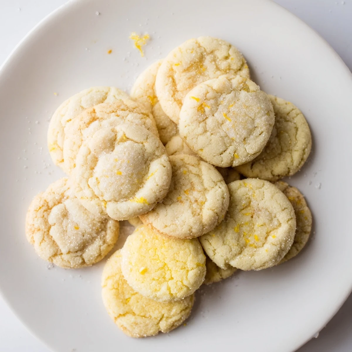 Soft chewy lemon cookies with golden edges and sugary coating on a white plate