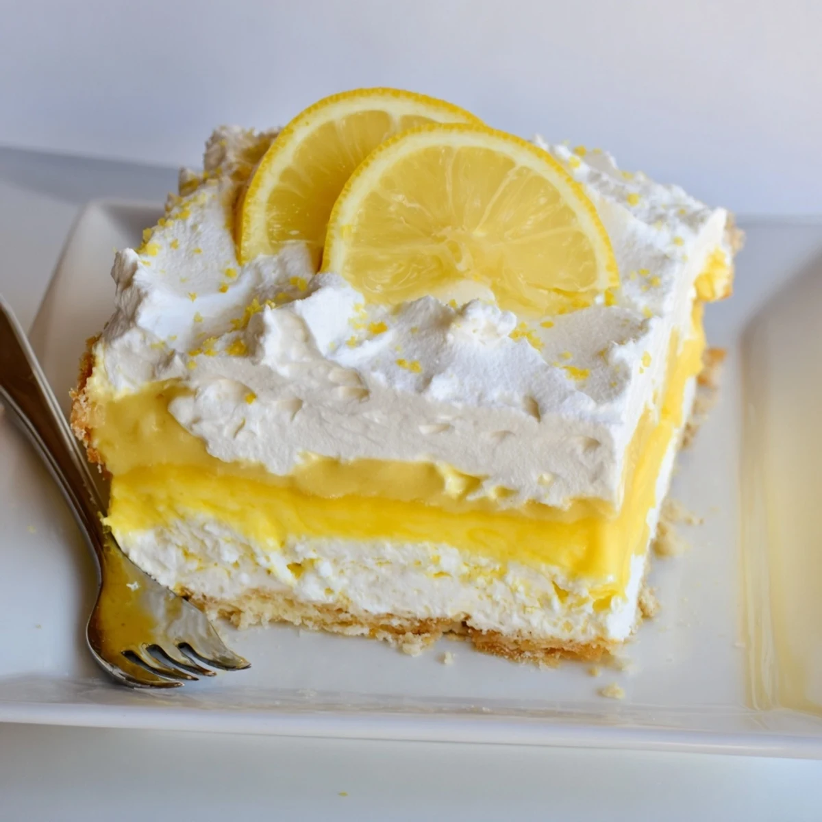 Fresh lemon lush cake slice with bright citrus pudding and buttery graham crust