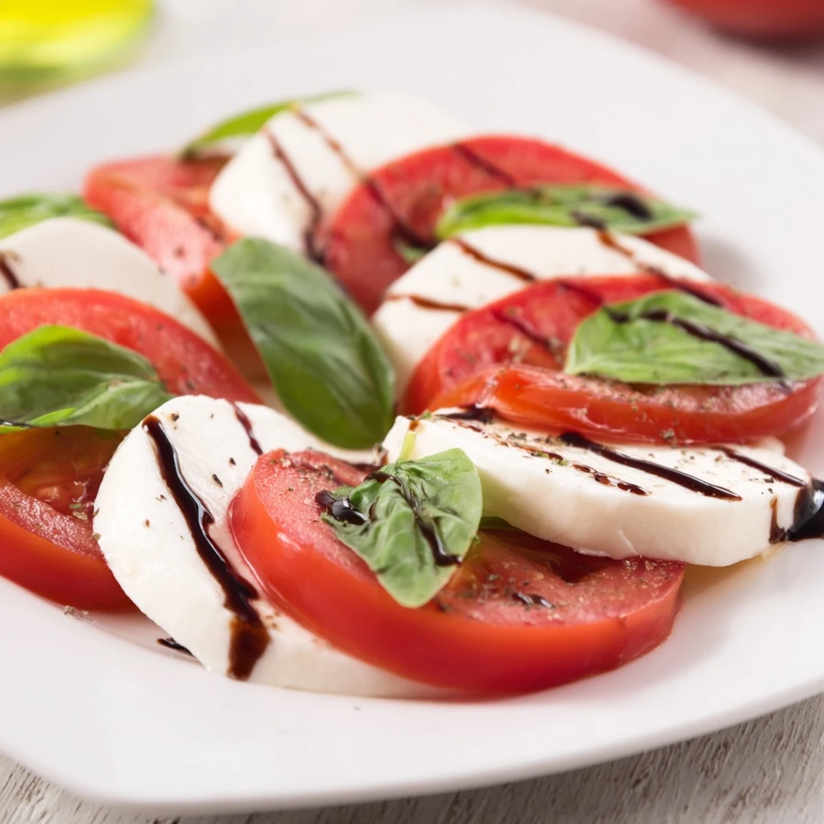 Bright summer platter showcasing Classic Caprese Salad drizzled with olive oil and balsamic.
