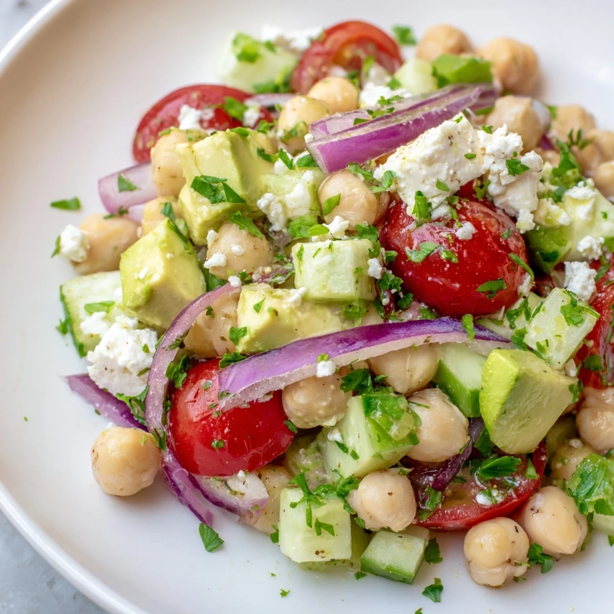 Bright and colorful chickpea feta avocado salad drizzled with zesty lemon herb dressing